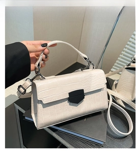 Dettaglio borsa bianca con trama a coccodrillo e chiusura geometrica nera di tendenza