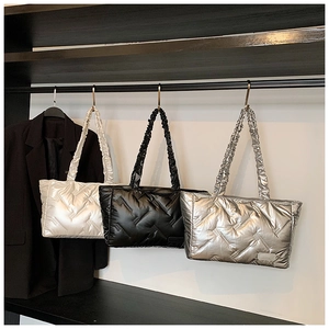 Close-up of quilted down tote bags in pearl white, black and silver on retail display
