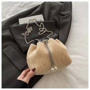 Detail of plush drawstring bucket bag with silver chain and pearl pendants on a blazer