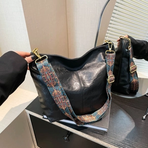 Large black leather tote bag with vintage patterned wide strap and bronze hardware
