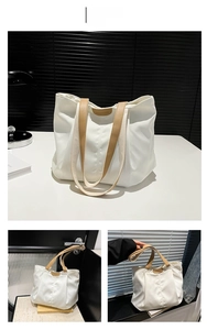 Detail of white canvas tote bag with brown leather handles and fashion logo patch
