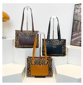 Three leopard print tote bags with solid color pockets displayed on white geometric blocks