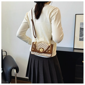 Détail d'un petit sac vintage à motif ondulé avec fermoir fleur dorée sur un mannequin