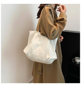 Detailed side view of the large white minimalist tote bag on a model's shoulder