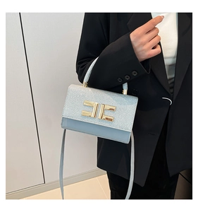 Detail of light blue crossbody bag with silver glitter flap and gold logo buckle