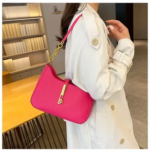 Detail of bright pink leather shoulder bag with gold hardware and stylish chain link