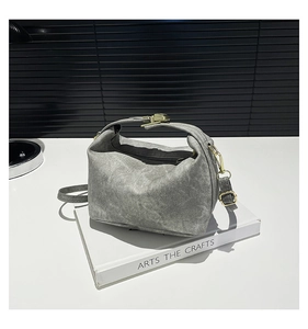Grey denim texture handbag with gold hardware shown on a minimalist white and black background