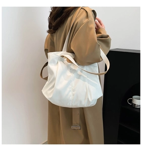 Minimalist white tote bag detail showing soft pleated fabric and shoulder strap design