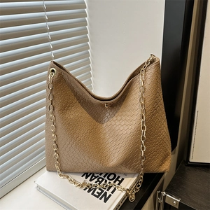 Beige woven shoulder bag with gold chain strap and metallic lock in natural light