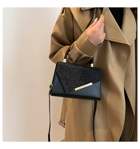 Detail of glitter patchwork and gold metal trim on elegant black crossbody flap bag