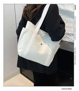 Close-up of white canvas tote bag featuring reinforced straps and metal button detail