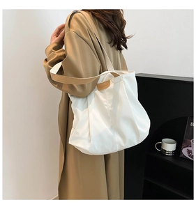 Detail of white pleated tote bag with fashion leather patch worn with a trench coat