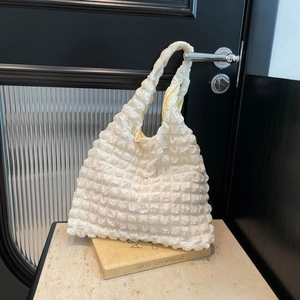Minimalist off-white popcorn texture puff tote bag hanging on a black door handle