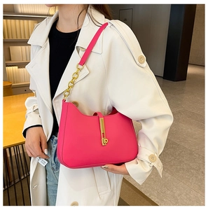 Detail of hot pink shoulder bag featuring gold hardware clasp and textured leather