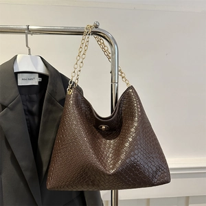 Retro brown woven chain shoulder bag with gold hardware shown on a display rack