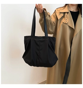 Detail of black nylon tote bag with fashion label and textured pleated surface