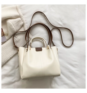 Detail of elegant PU leather tote bag with contrast brown handles and gold hardware accents