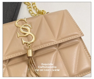 Macro view of geometric quilted beige faux leather with gold tassel logo and fine stitching