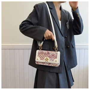 Détail du sac bandoulière vintage avec broderie florale et fermoir fleur dorée