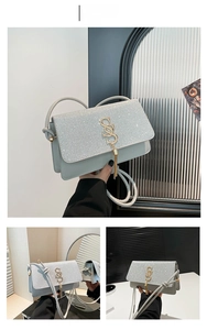 Detail of silver glitter crossbody bag featuring a golden S logo with chain tassels