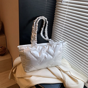 Silver quilted puffer tote bag with ruched handle on a blazer for a stylish look