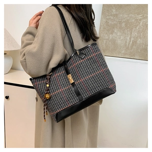 Detail view of large houndstooth tote bag with black leather straps and gold twist lock