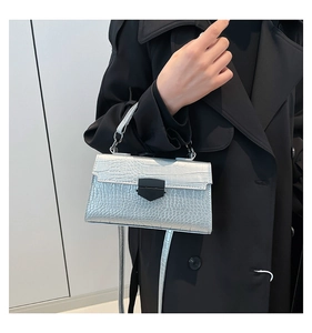 Dettaglio borsa a mano argento texture coccodrillo con fibbia nera su sfondo cappotto nero