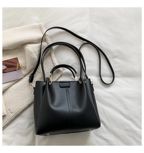 Detailed view of black PU tote with gold cylindrical metal hardware and vertical stitching