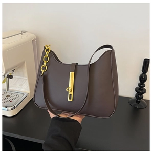 Close-up of chocolate brown leather shoulder bag with gold chain and metal lock