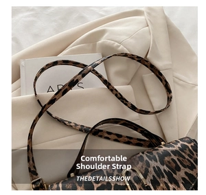 Close-up of leopard print shoulder strap and gold buckle detail on a fashion bag