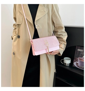 Close-up of pink sequined crossbody bag with golden S-buckle and tassel detail