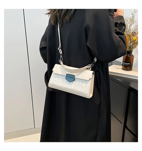 Dettaglio della borsa a mano crema a trama coccodrillo con fibbia a scudo blu elegante