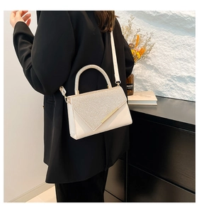Detail of a chic cream handbag with sparkling rhinestones and elegant gold hardware