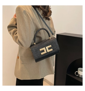 Détail du sac bandoulière noir scintillant avec logo doré et texture brillante