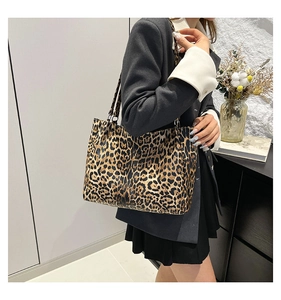 Close-up of leopard print tote bag texture and black shoulder straps in a modern interior