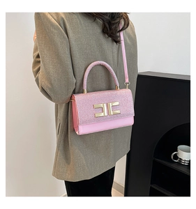 Close-up of pink glitter handbag with gold buckle styled on a shoulder by a model