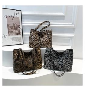 Close-up of leopard print tote bags in yellow, brown, and grey on a white display stand