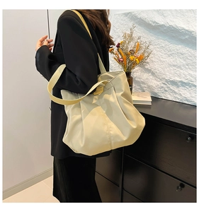 Close-up of cream canvas tote bag with 'FASHION' metal detail on wide shoulder strap