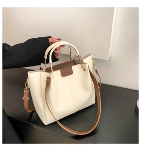 Detail of cream PU tote bag with brown leather straps and gold U-shaped metal buckle