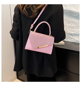 Detail of pink sequin handbag featuring a gold metallic bar and hard top handle