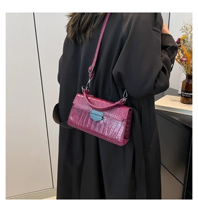 Dettaglio borsa bordeaux motivo coccodrillo con chiusura argento e tracolla sottile