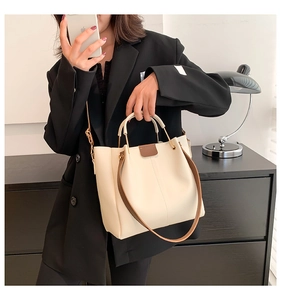 Detail of minimalist cream PU tote bag with brown handles and golden metal rings