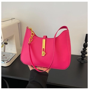 Detail of rose pink handbag featuring a sleek gold metal lock and decorative chain handle