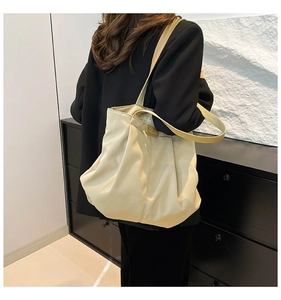 Detail of a beige oversized tote bag with pleated top and FASHION label on model