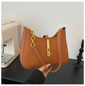Detail of caramel leather shoulder bag with vertical gold lock and metal chain strap