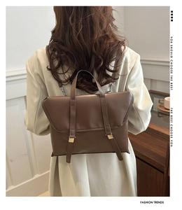 Detail of vintage brown leather backpack with parallel straps and gold metal buckles