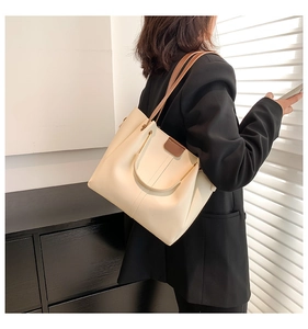 Detail of minimalist cream tote bag with brown straps and golden metal hardware joints