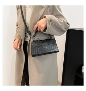 Modella che indossa una borsa nera a motivo coccodrillo con un cappotto beige