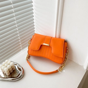 Detail of orange tote bag featuring vertical stitching and a gold metal chain strap