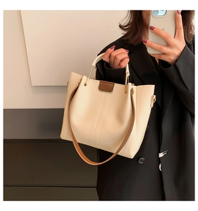 Detail of cream tote bag featuring brown contrast straps and premium gold hardware
